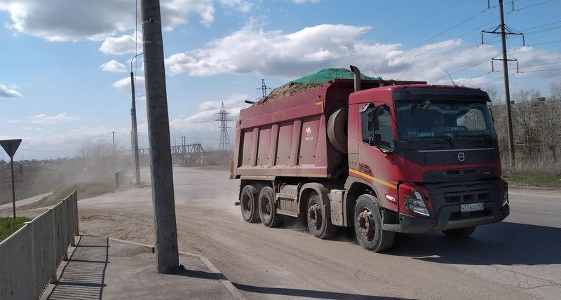 Тяжелые грузовики разбивают городские дороги, к тому же за ними тянется шлейф песчаной пыли
